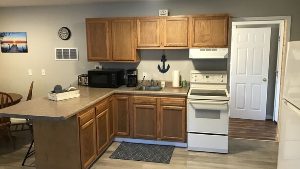 Una cocina con armarios de madera, microondas, cafetera, estufa y lavabo.