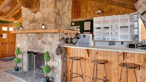 Ein rustikales Interieur mit Kamin aus Stein, hölzernen Barhocker und einer Steinsäule.