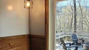 Ein Blick in einen Raum zeigt eine Holzwand, einen Korbwannenkorb mit der Aufschrift ‚MAKEUP‘ auf einem Stuhl und einen Ausblick auf eine Terrass mit Stühlen und Tisch.