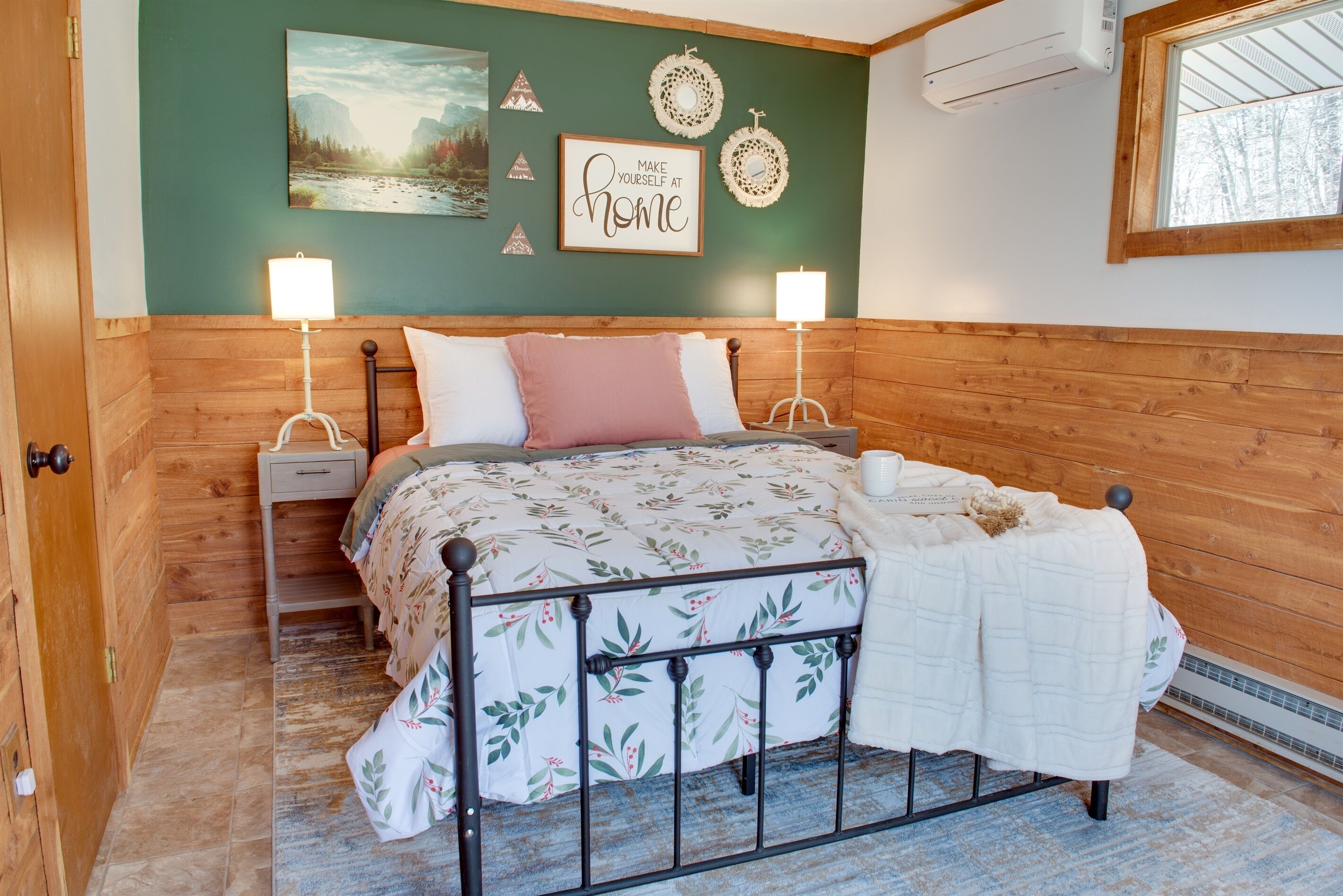 Une chambre à coucher comprenant un lit, deux tables de chevet, un climatiseur mural et des éléments de décoration murale.