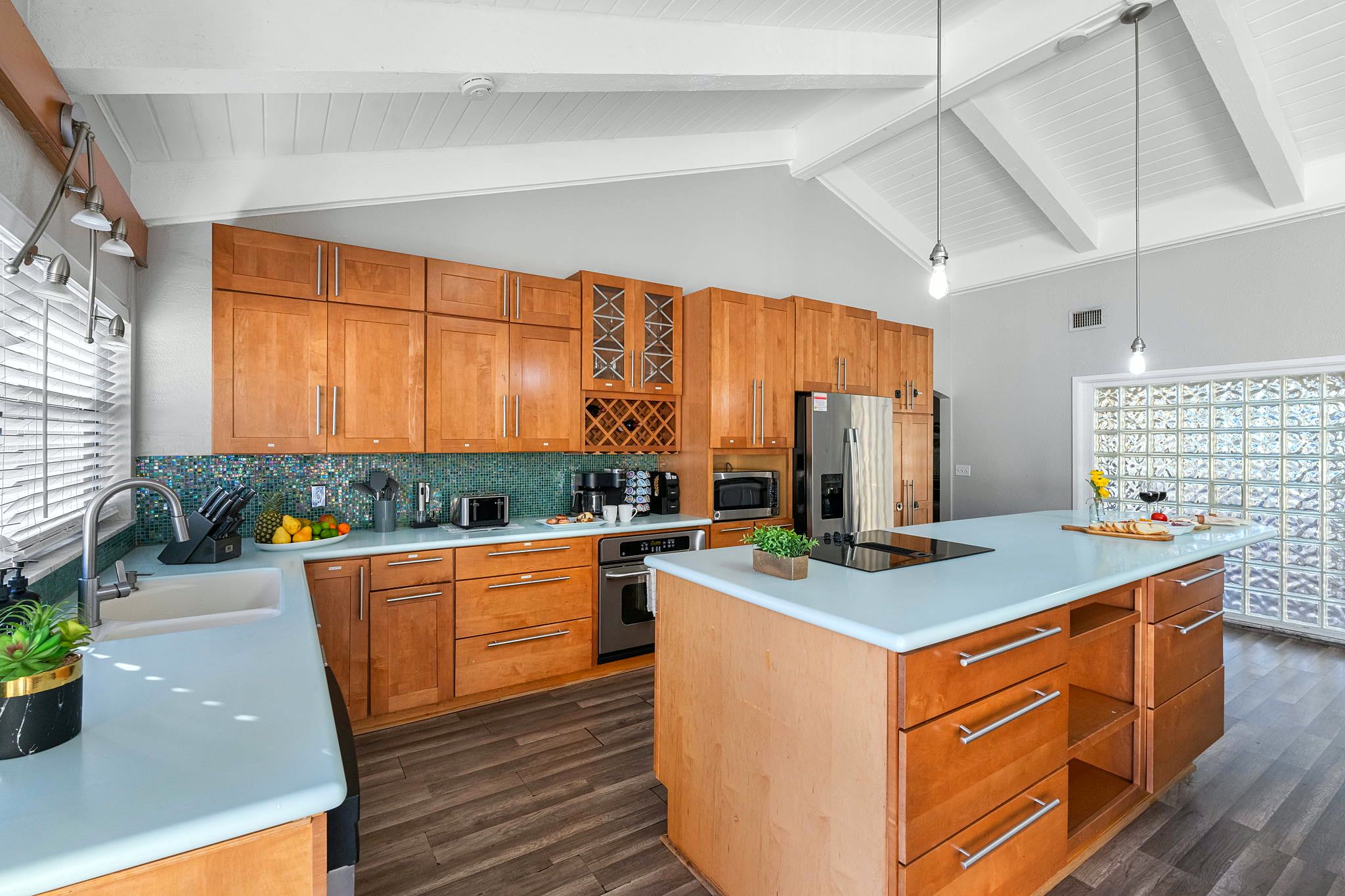 A modern kitchen with wooden cabinets, a central island, and a backsplash with a mosaic tile pattern.