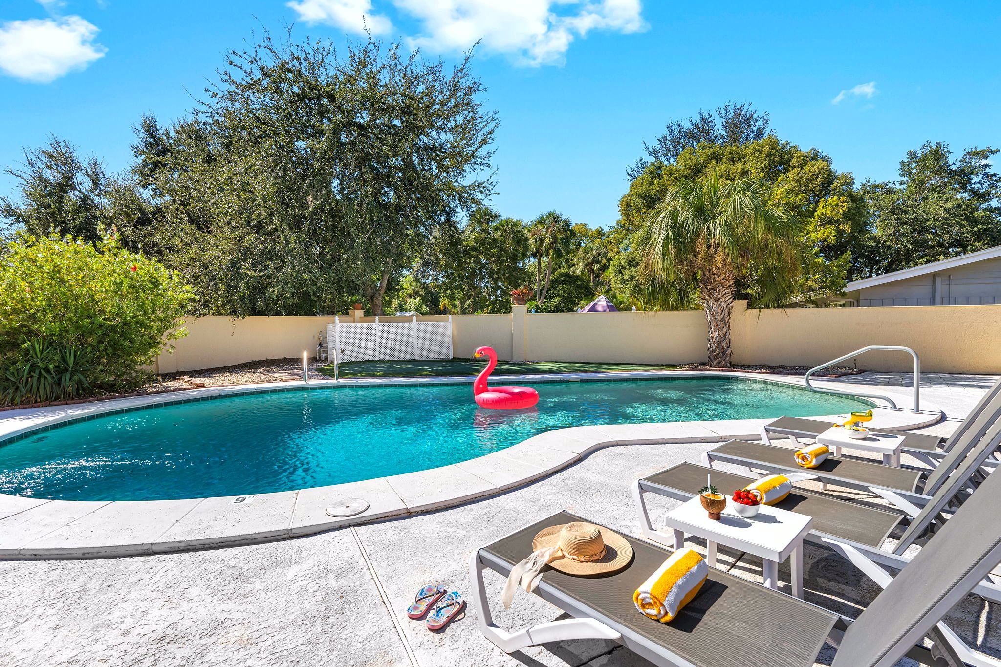 A swimming pool with lounge chairs and a flamingo float.