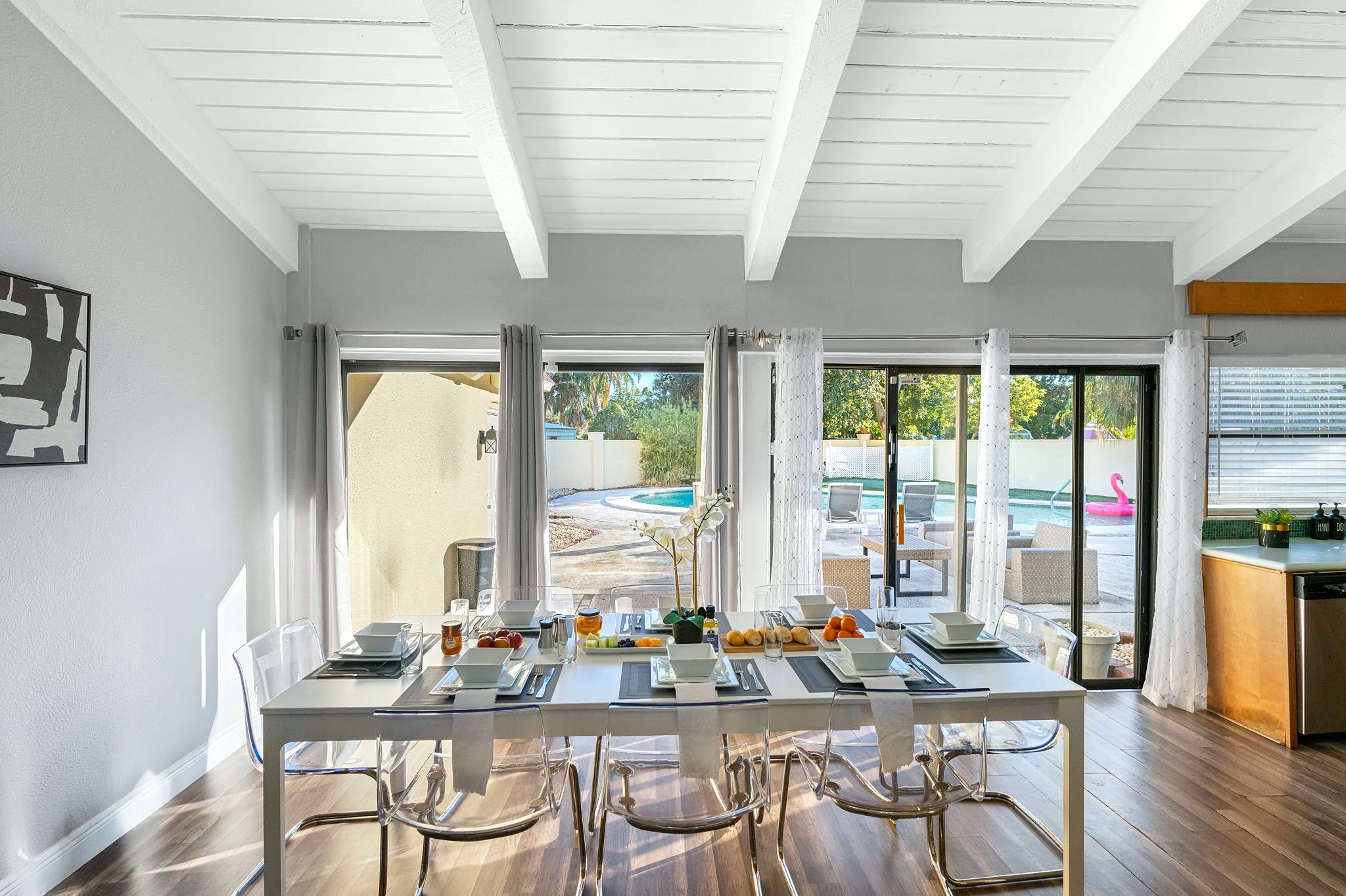 A dining area with a table set for four, large windows, and a view of a swimming pool.