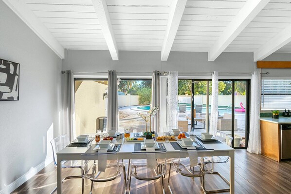 A dining area with a table set for four, large windows, and a view of a swimming pool.