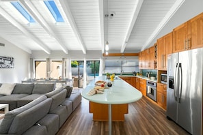 A modern kitchen with a central island, wooden cabinets, and a stainless steel refrigerator.