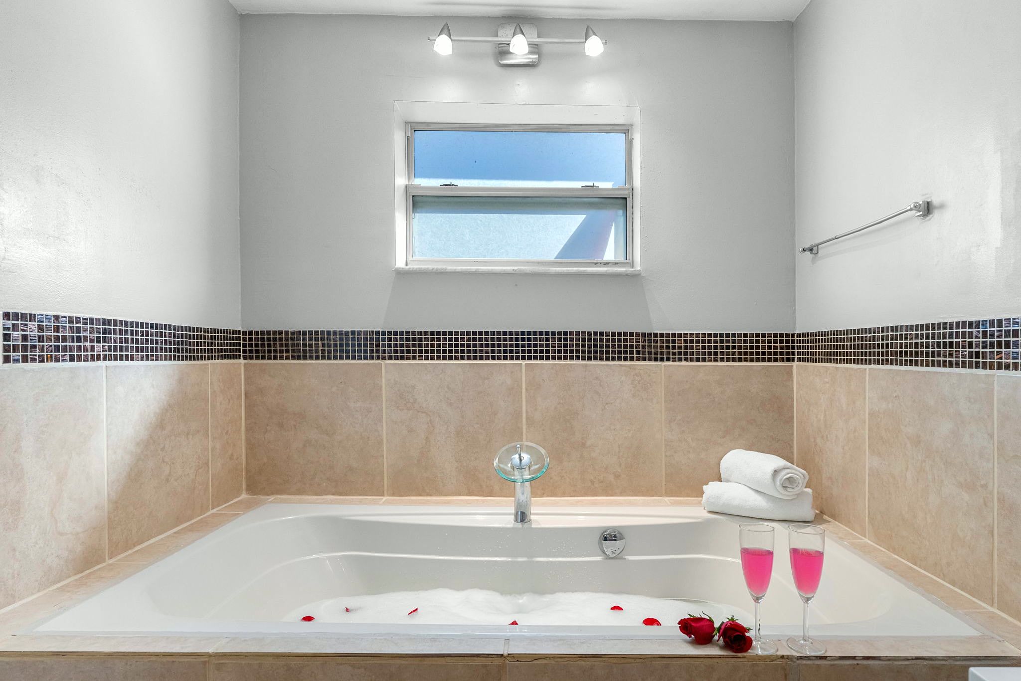 A bathroom with a bathtub, a window, and a towel rack.
