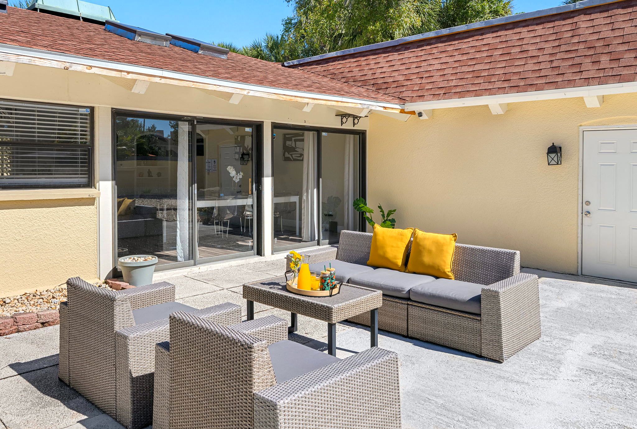 A patio area with wicker furniture, a table with a tray of items, and a sliding glass door leading to an indoor space.