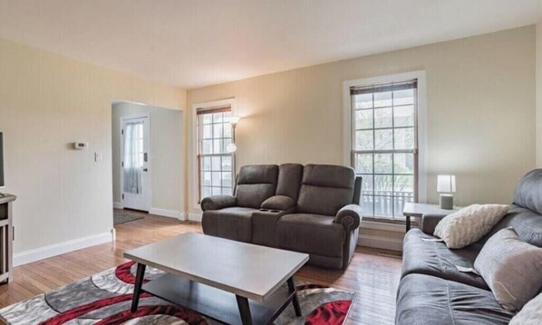 A living room with a sofa, a coffee table, and a door leading to another room. - Furnished Private home in Aurora sleeps 9 guests (Aurora)