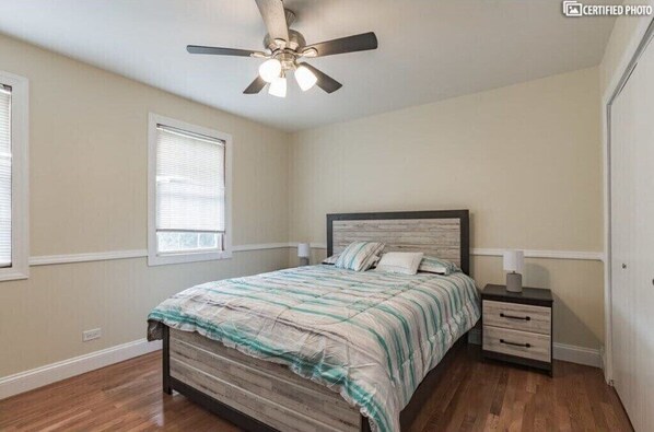 A bedroom with a bed, nightstands, a ceiling fan, and a window. - Furnished Private home in Aurora sleeps 9 guests (Aurora)