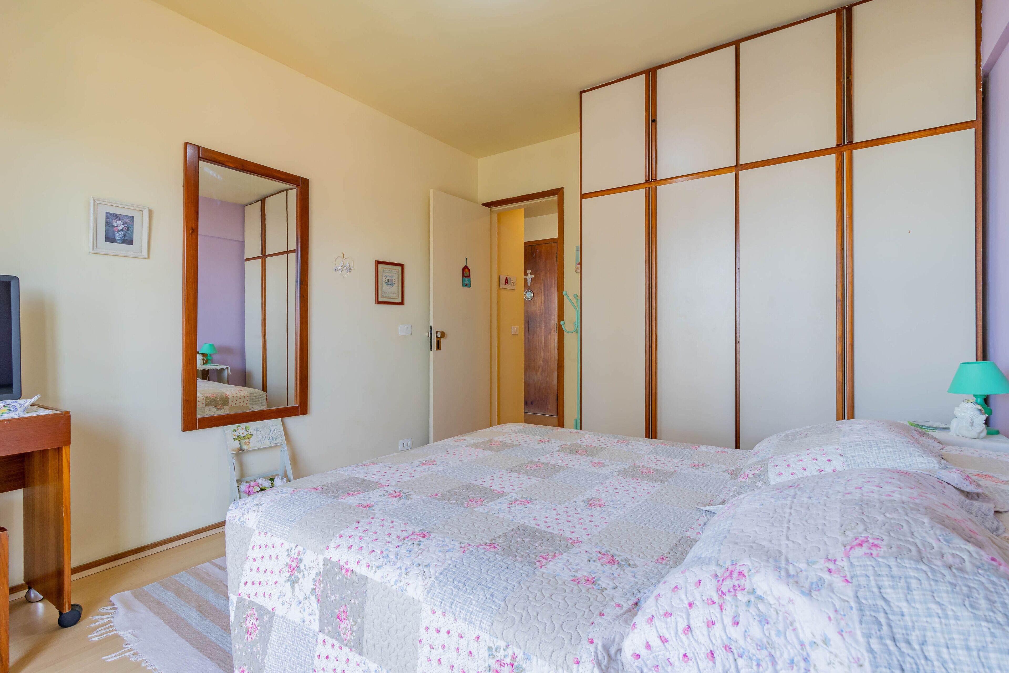 Un dormitorio con cama, cómoda, espejo y armario.
