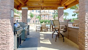 Une terrasse extérieure dotée d’un espace barbecue, de murs en pierre et de mobilier d’extérieur.