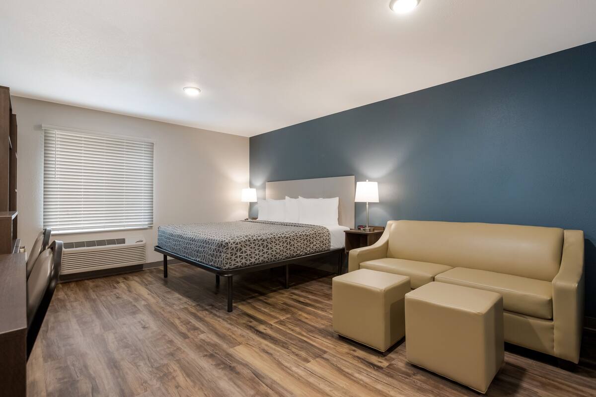 A hotel room with a bed, bedside lamps, a sofa, and a small table.