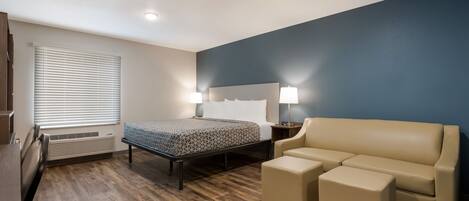 A hotel room with a bed, bedside lamps, a sofa, and a small table.