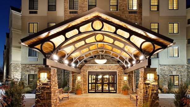 L’entrée d’un hôtel avec une façade en pierre, un patio couvert et un hall d’entrée bien éclairé.