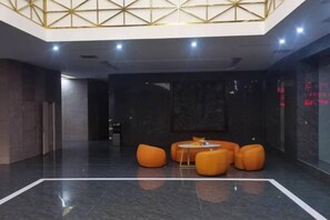 A lobby with a high ceiling, a marble floor, and orange seating. - Zhenfeng Hotel (Zhenfeng)