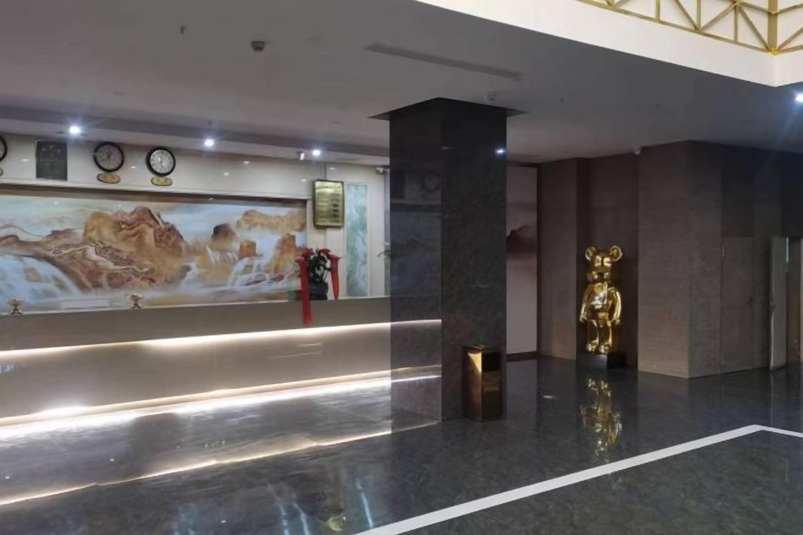 A reception area with a marble floor, a reception desk, a wall-mounted clock, and a golden statue.
