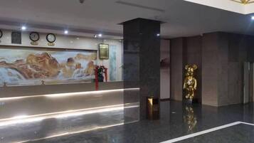 A reception area with a marble floor, a reception desk, a wall-mounted clock, and a golden statue.