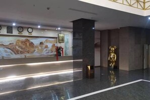 A reception area with a marble floor, a reception desk, a wall-mounted clock, and a golden statue. - Zhenfeng Hotel (Zhenfeng)
