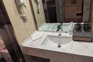A bathroom with a white sink, a mirror, a towel, and toiletries. - Zhenfeng Hotel (Zhenfeng)