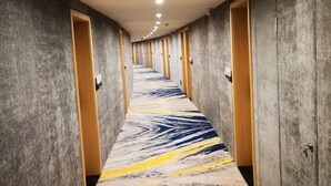 Un pasillo con alfombra estampada, puertas de madera e iluminación empotrada en el techo.