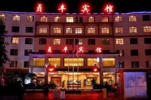 Un hotel con una entrada destacada, varios pisos y señalización iluminada.