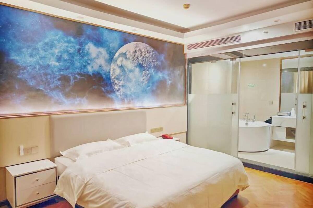 Quarto de hotel com uma cama grande, mesa de cabeceira, armário e banheiro com espelho e pia.