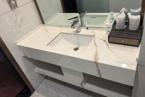 A bathroom with a white sink, a mirror, and a towel dispenser. - Zhenfeng Hotel (Zhenfeng)