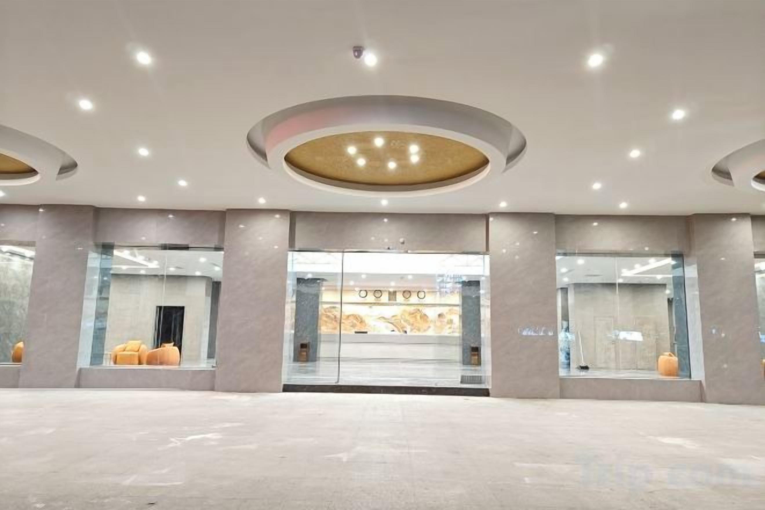A spacious lobby with a modern design, featuring a large glass entrance, recessed lighting, and a clean, minimalist aesthetic.