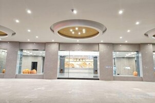 Un vestíbulo amplio con diseño moderno, que presenta una gran entrada de cristal, iluminación empotrada y una estética limpia y minimalista.