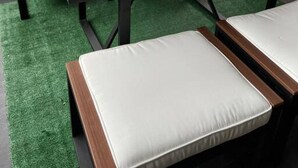 A patio area with a wooden table and white cushioned seating.