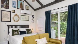 Une chambre à coucher avec un lit, un canapé jaune et une grande fenêtre avec des rideaux.