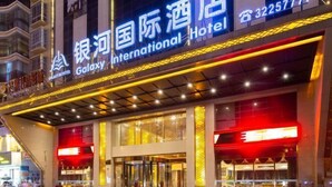 El exterior del Hotel Galaxy International, con señalización iluminada y una fachada moderna.