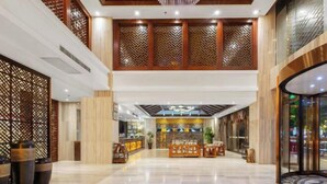 A spacious lobby with a reception desk, seating area, and decorative wooden panels. - Galaxy International Hotel (Zhenning)