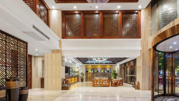 Un vestíbulo amplio con mostrador de recepción, zona de estar y paneles decorativos de madera.
