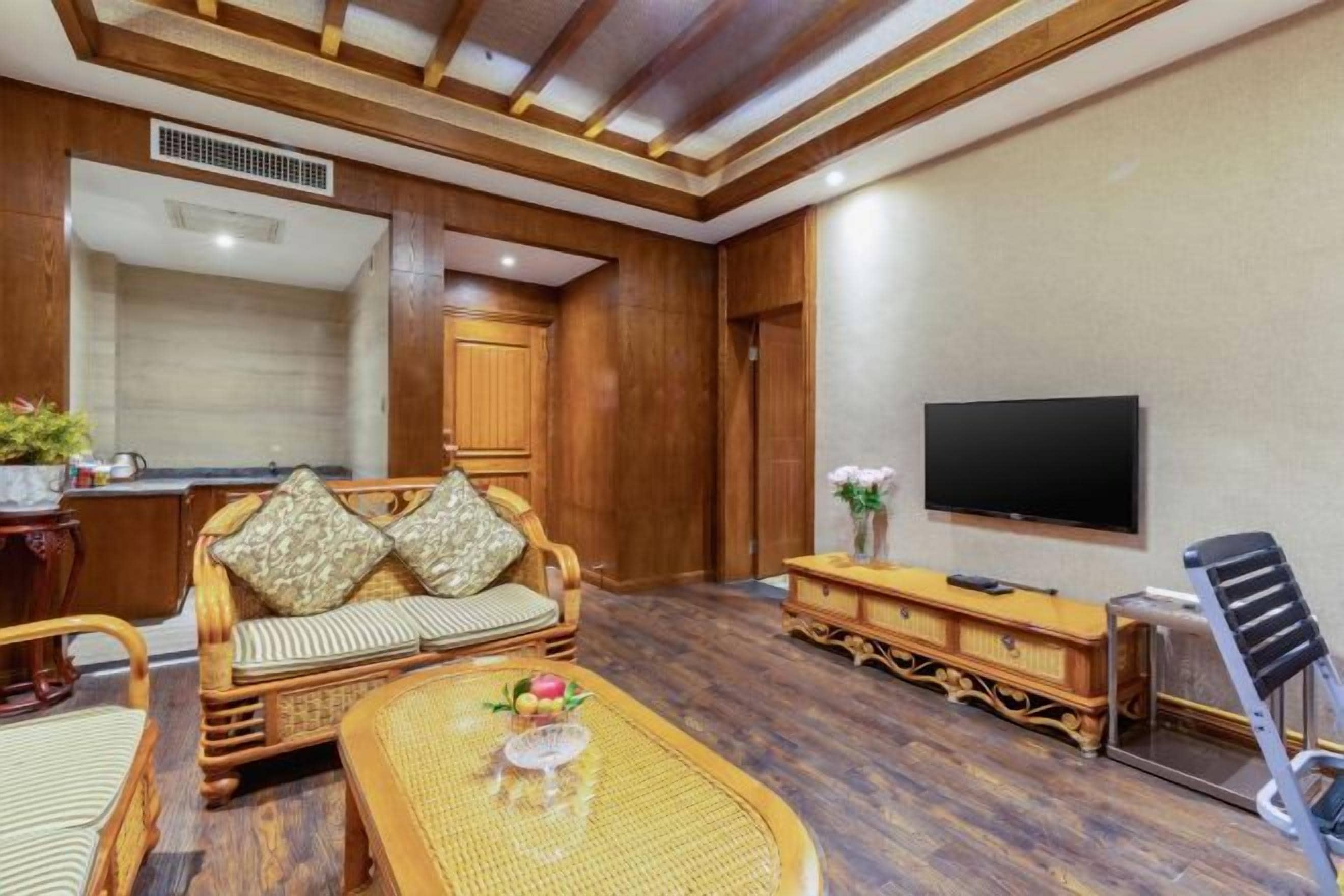 A room with a sofa, a coffee table, a television, and a wooden cabinet.