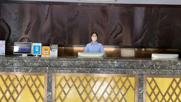 A reception desk with a modern design, featuring a patterned wall and a marble countertop. - Galaxy International Hotel (Zhenning)
