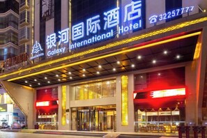 A hotel entrance with a prominent sign, large glass doors, and a covered walkway. - Galaxy International Hotel (Zhenning)