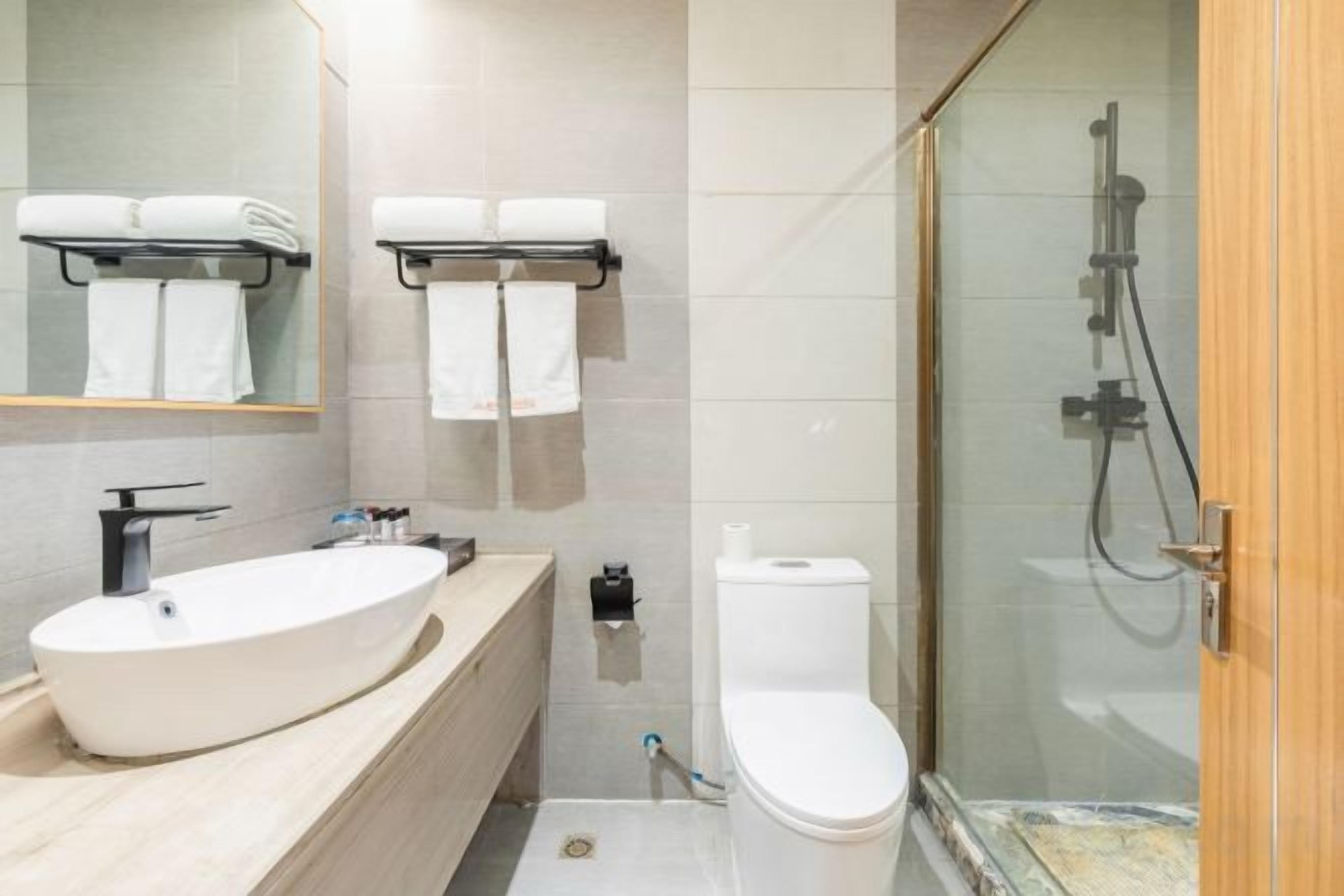 Un baño moderno con un lavamanos grande, inodoro y ducha con mampara de vidrio.
