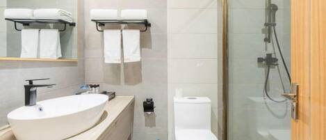 Un baño moderno con un lavamanos grande, inodoro y ducha con mampara de vidrio.
