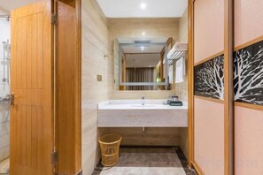 A bathroom with a wooden door, a sink, a mirror, and a towel rack. - Galaxy International Hotel (Zhenning)