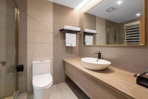 A modern bathroom with a toilet, a large mirror, and a sink on a wooden countertop. - Galaxy International Hotel (Zhenning)