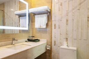 A bathroom with a large mirror, a sink, and a toilet. There are towels hanging on a rack. - Galaxy International Hotel (Zhenning)