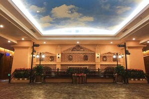 Un vestíbulo de hotel con techo alto, pared de ladrillo con diseño decorativo y una recepción.