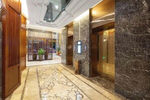 A hotel lobby with a marble floor, a reception desk, and an elevator. - Galaxy International Hotel (Zhenning)