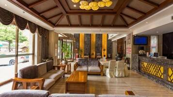 A hotel lobby with seating areas, a reception desk, and large windows.