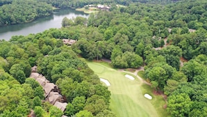 An aerial view of a golf course surrounded by dense forest, with several buildings likely serving as accommodations or facilities. - Fairway to Seven - King Bed, Big-screen TVs & Golf Course Views (Jasper)