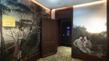 Un pasillo con un mural, una puerta y una pantalla digital.