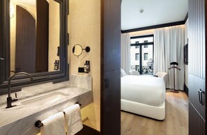 A hotel room with a marble bathroom, a large mirror, a bed, and a view of the city. - Hotel Montera Madrid, Curio Collection By Hilton (Madrid)