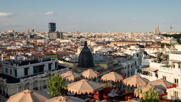 Panoramic city views from a public space with seating areas and a prominent historical building featuring a large dome.