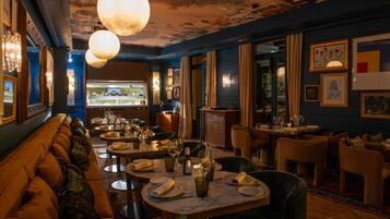 Un interior de restaurante con mesas redondas, sillas y una zona de bar.